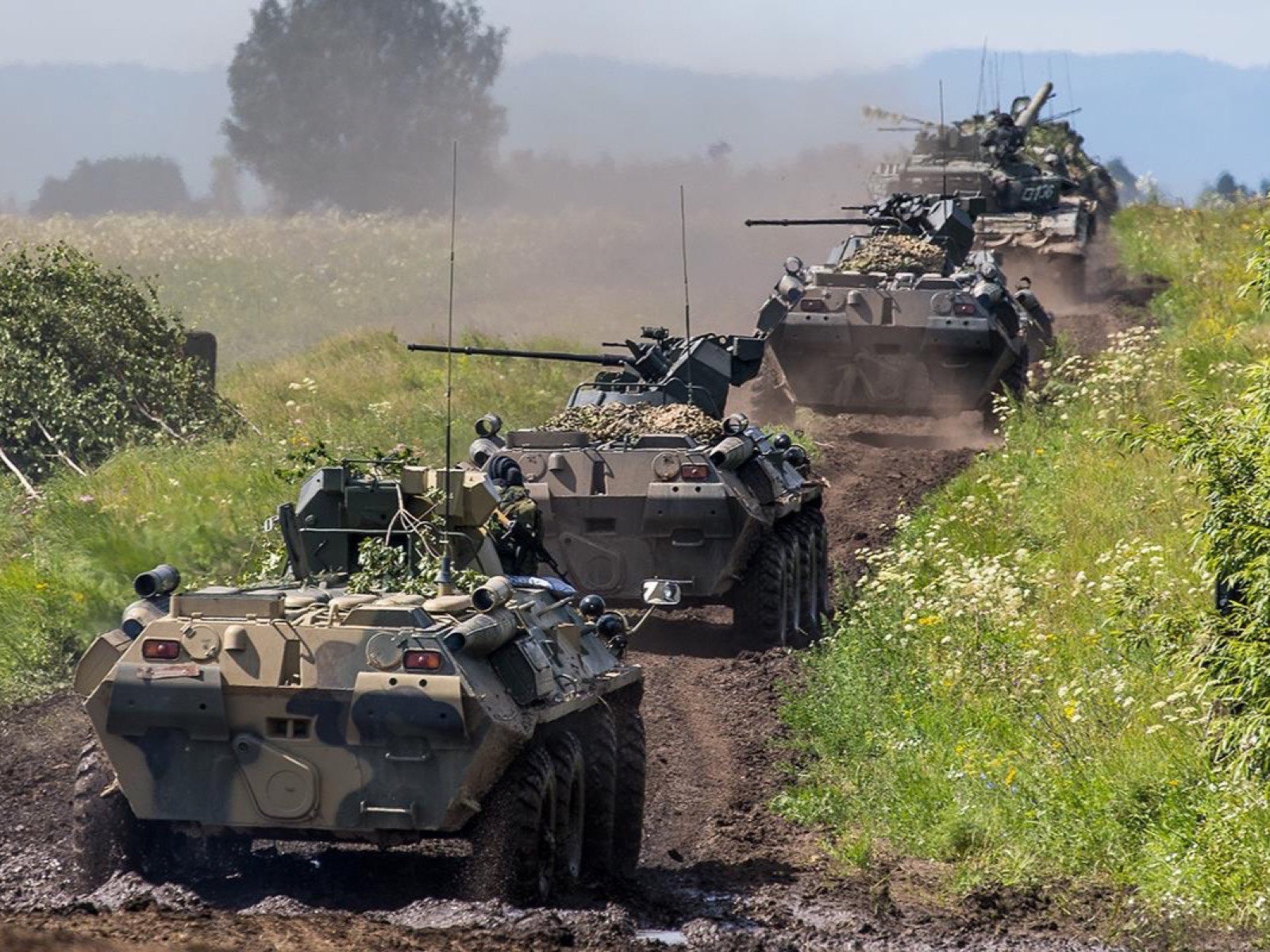 Колонна БТР-82А на грунтовой дороге на полевом учении, за ними идут танки