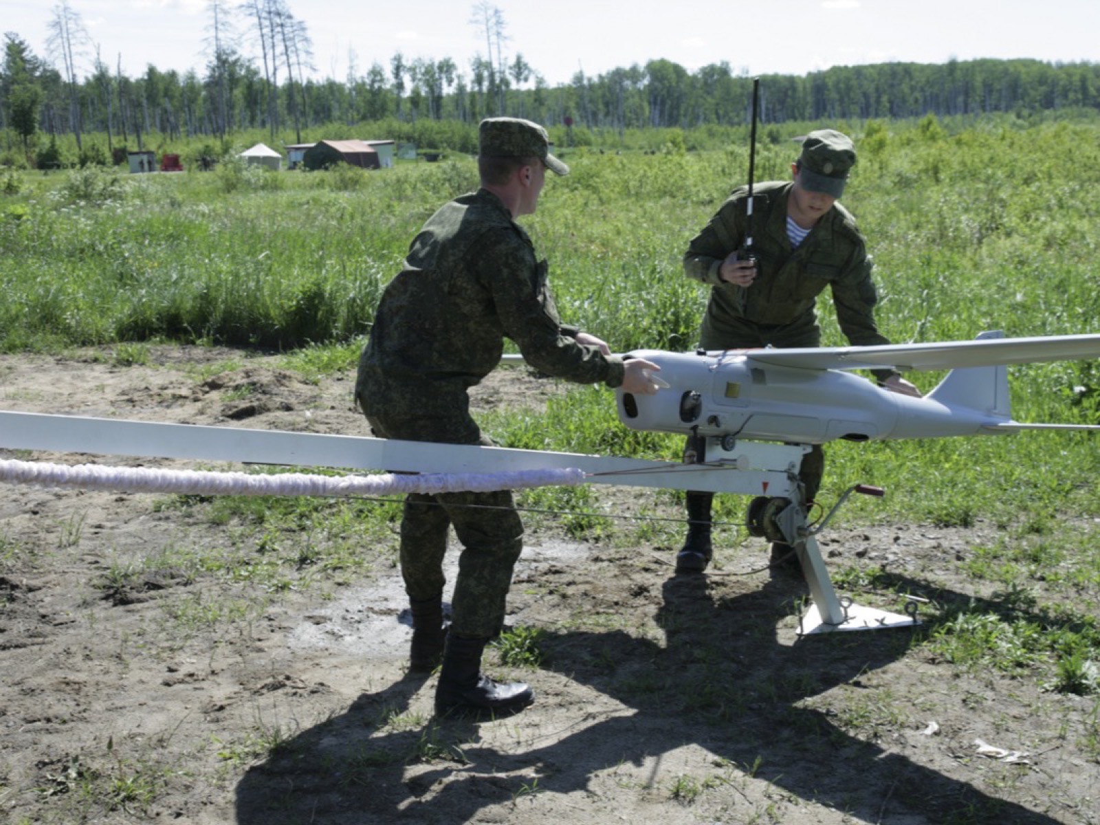 Расчёт БПЛА «Орлан-10»: двое военнослужащих на поле готовят аппарат на катапульте, у одного рация